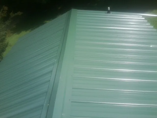 New green metal panels meeting at the ridge of a roof — Flat Roof Repair work by our crew in Springfield
